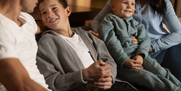 Famille souriante assise sur un canapé.