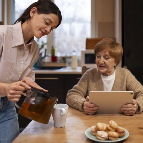 Femme sert du thé à une personne âgée.