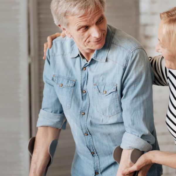 Personne avec des béquilles se faisant soutenir par quelqu'un.