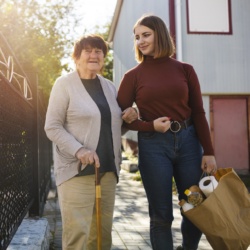 Femme aidant une vieille dame avec courses.