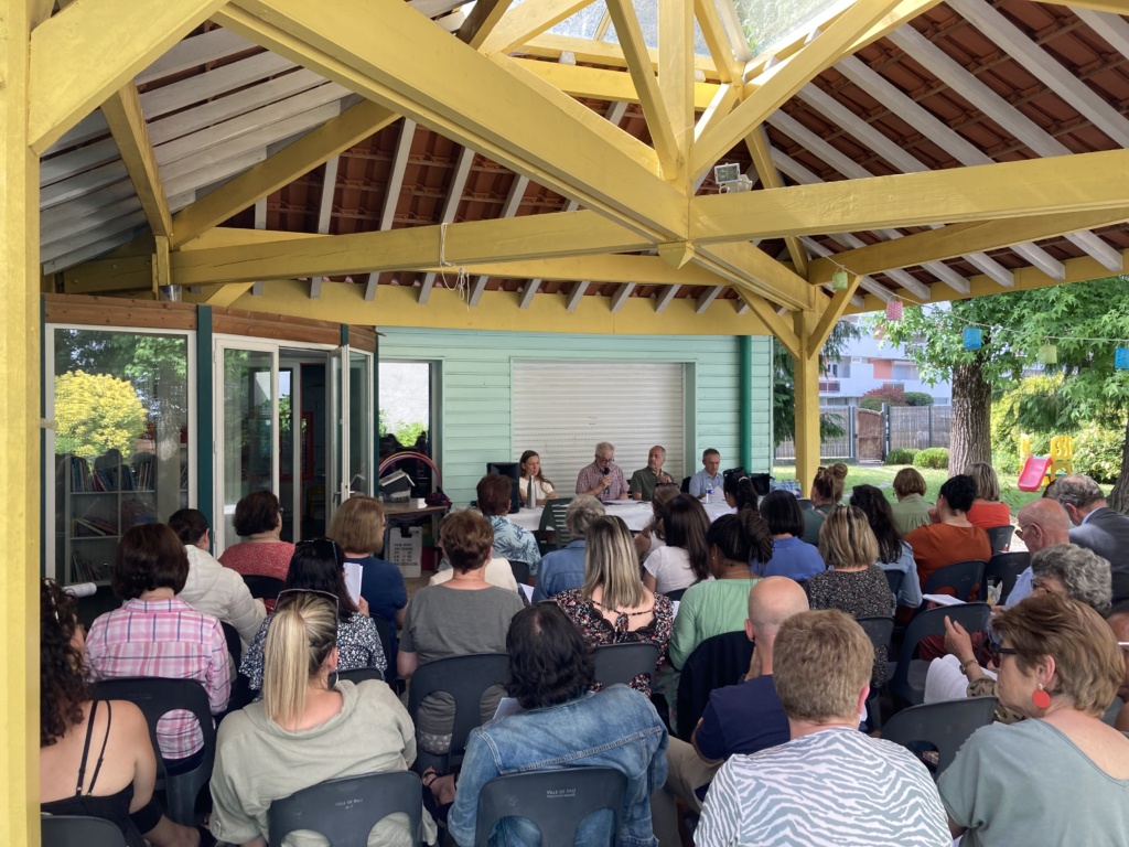 Réunion d'assemblée générale en plein air sous un abri en bois.