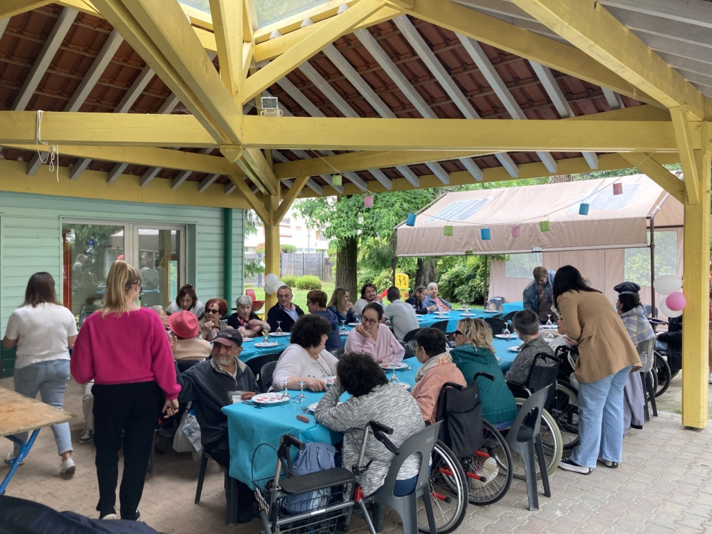 Groupe de personnes en situation de handicap et les personnes accompagnées partageant un repas sous un abri.